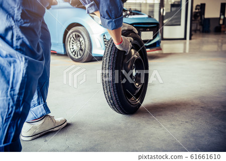 Car mechanics changing tire at auto repair shop 61661610
