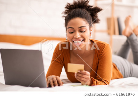 Lady Using Credit Card And Laptop Lying In Bed Indoor 61661970