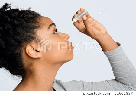 Young woman applying ophthalmology eyedropper, glaucoma eye prevention 61662857