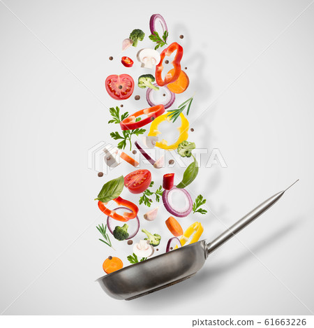 Frying pan with flying vegetables on white Frying pan with flying vegetables on white 61663226