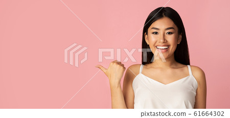 Charming asian girl pointing fingers aside at free space 61664302