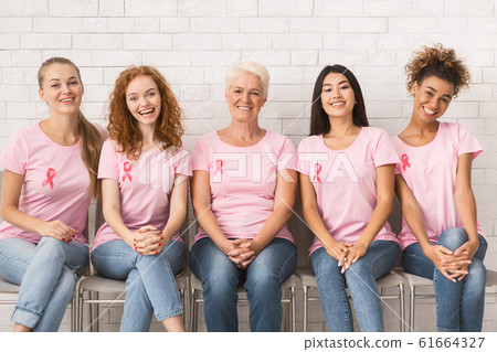Multiracial Women In Pink Awareness T-Shirts Sitting On Chairs Indoor Multiracial Women In Pink Awareness T-Shirts Sitting On Chairs Indoor 61664327