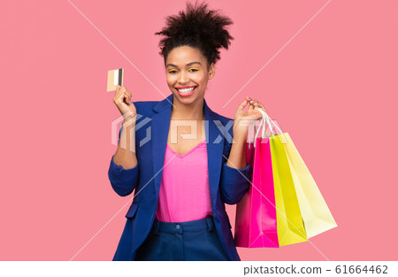 Cheerful black woman with shopping bags and plastic card Cheerful black woman with shopping bags and plastic card 61664462