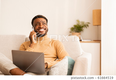 Happy Black Man Talking On Cellphone Working On Laptop Indoor Happy Black Man Talking On Cellphone Working On Laptop Indoor 61664519