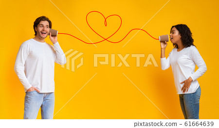 Affectionate afro girl singing love song to boyfriend through tin phone 61664639