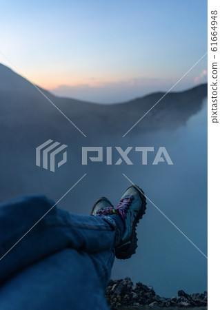 Adventure seeker sitting on the cliff and enjoying 61664948
