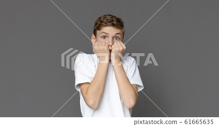 Scared teen boy looking at camera with amazement 61665635