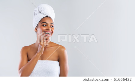 Happy black woman wrapped in towels looking at copy space Happy black woman wrapped in towels looking at copy space 61666422