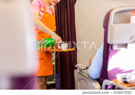 Flight attendant serving drinks to passengers on board. Flight attendant serving drinks to passengers on board. 61667092