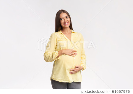 Pregnant Lady Smiling To Camera Touching Belly Over White Background Pregnant Lady Smiling To Camera Touching Belly Over White Background 61667976