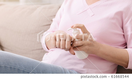 Mature woman moisturizing hand skin with lotion 61668544