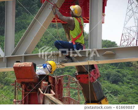 Construction workers working at height installing the steel structure. Steel structure able to provide huge and long span for the building. Construction workers working at height installing the steel structure. Steel structure able to provide huge and long span for the building. 61669887