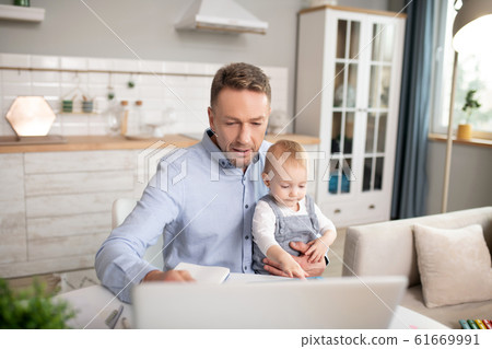 Man in a blue shirt spending time with his cute baby daughter Man in a blue shirt spending time with his cute baby daughter 61669991