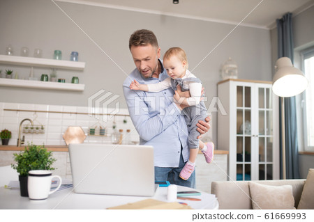 Man in a blue shirt standing and looking at the laptop Man in a blue shirt standing and looking at the laptop 61669993