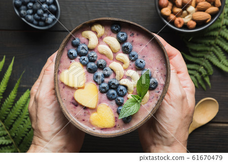 Banana and blueberry smoothie in woman hands. Banana and blueberry smoothie in woman hands. 61670479