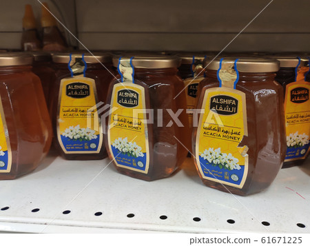 Honey packed in plastic bottles. Displayed for sale on the shelf inside the supermarket. Honey packed in plastic bottles. Displayed for sale on the shelf inside the supermarket. 61671225