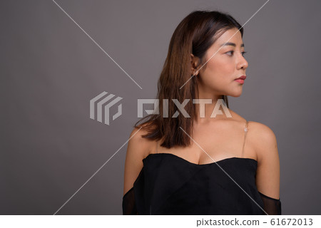 Young beautiful Asian woman against gray background 61672013