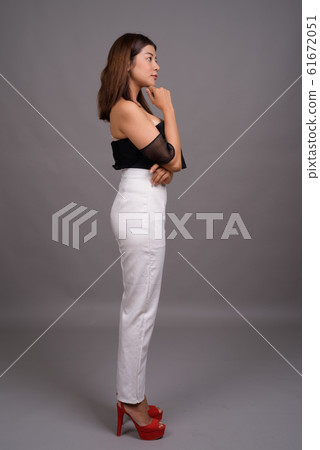 Young beautiful Asian woman against gray background Young beautiful Asian woman against gray background 61672051
