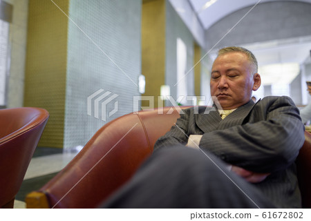 Mature Asian businessman relaxing inside the coffee shop Mature Asian businessman relaxing inside the coffee shop 61672802