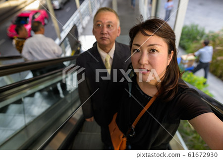 Mature Asian businessman and mature Asian woman exploring the city together 61672930