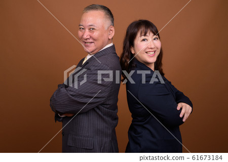 Happy mature Asian businessman and mature Asian businesswoman smiling together Happy mature Asian businessman and mature Asian businesswoman smiling together 61673184