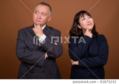 Mature Asian businessman and mature Asian businesswoman thinking together Mature Asian businessman and mature Asian businesswoman thinking together 61673232