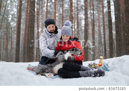 young couple with dog have picnic in snowy forest young couple with dog have picnic in snowy forest 61673285