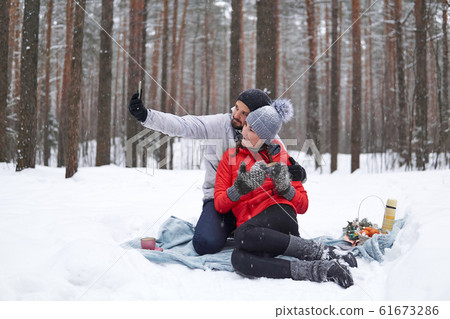young couple have picnic in snowy forest, take young couple have picnic in snowy forest, take 61673286