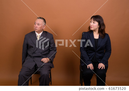 Mature Asian businessman and mature Asian businesswoman thinking together 61673520