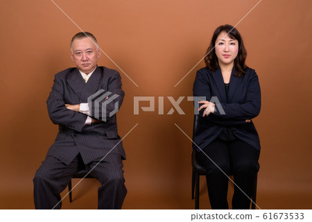 Mature Asian businessman and mature Asian businesswoman sitting together Mature Asian businessman and mature Asian businesswoman sitting together 61673533