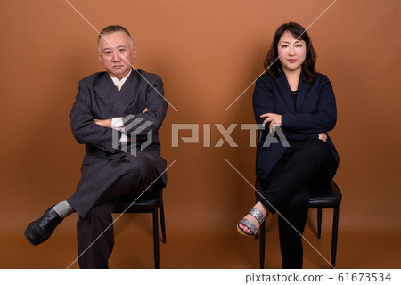 Mature Asian businessman and mature Asian businesswoman sitting together Mature Asian businessman and mature Asian businesswoman sitting together 61673534