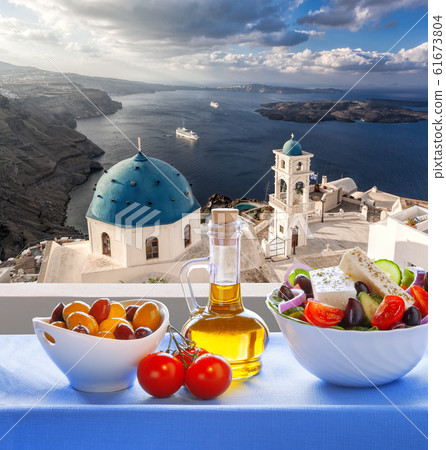 Greek salad against famous church in Thira town on Santorini island in Greece Greek salad against famous church in Thira town on Santorini island in Greece 61673804
