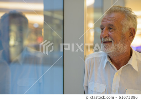 Handsome senior tourist man relaxing inside the mall 61673886