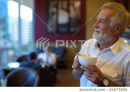 Handsome senior tourist man relaxing inside the coffee shop 61673890