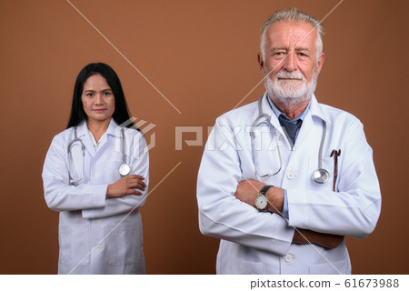 Mature multi-ethnic couple doctors against brown background Mature multi-ethnic couple doctors against brown background 61673988