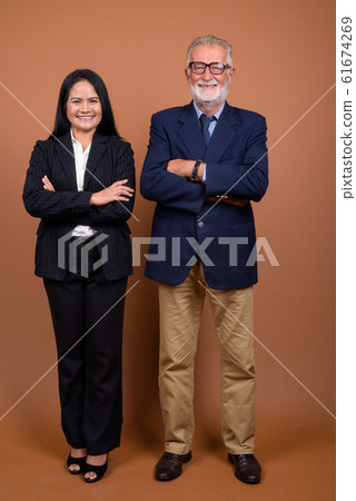 Mature multi-ethnic business couple against brown background 61674269
