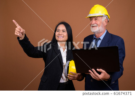 Mature multi-ethnic business couple against brown background 61674371