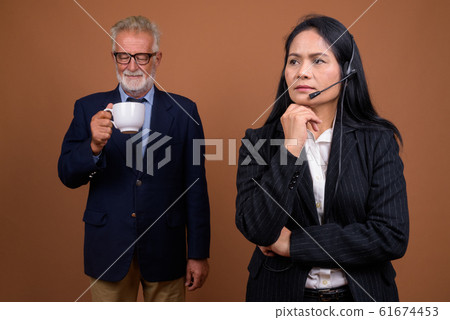 Mature multi-ethnic business couple against brown background 61674453