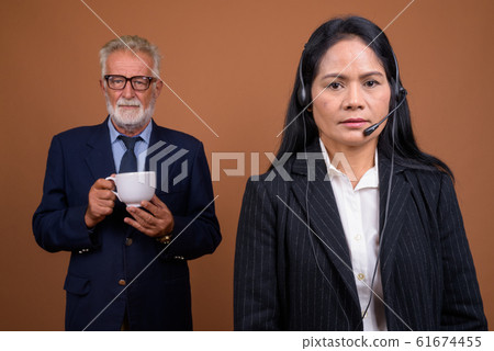 Mature multi-ethnic business couple against brown background 61674455