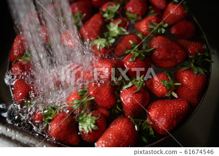 Juicy ripe red strawberries are washed in a steel bowl full of water. 61674546