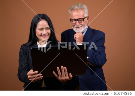 Mature multi-ethnic business couple against brown background 61674556