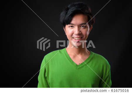 Young handsome Asian man against black background 61675016