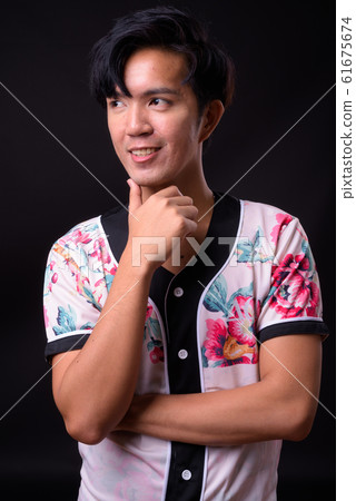 Young handsome Asian man against black background 61675674