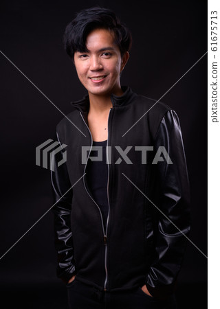 Young handsome Asian man against black background Young handsome Asian man against black background 61675713