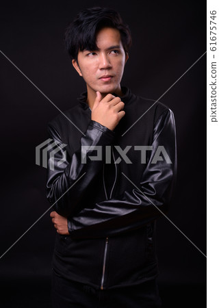Young handsome Asian man against black background Young handsome Asian man against black background 61675746