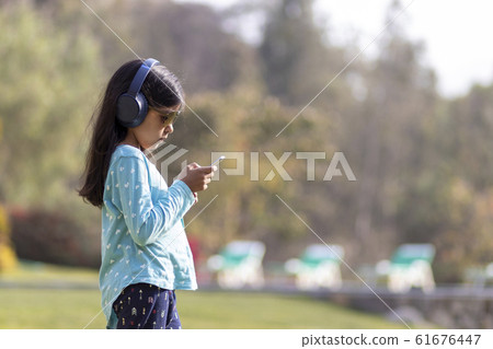 Little girl listening to music on the smartphone Little girl listening to music on the smartphone 61676447