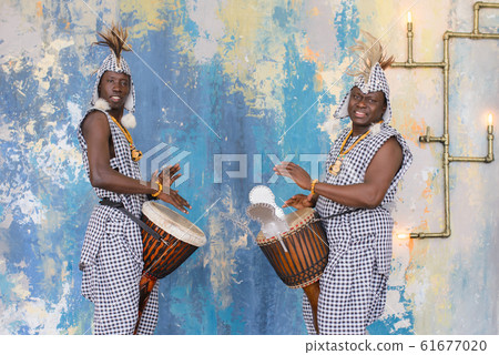 A group of people in traditional african costumes playing jembe drums 61677020