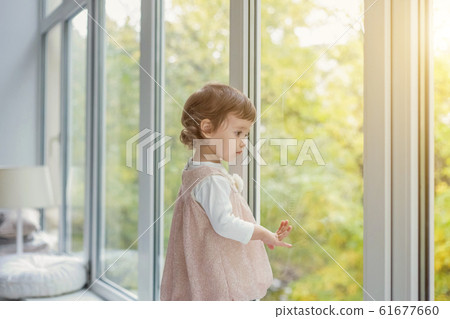 Little girl standing on window sill 61677660
