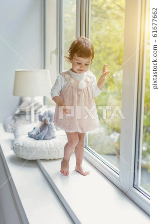 Little girl standing on window sill 61677662