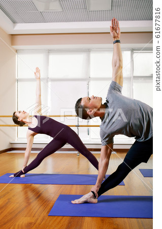 Group of sporty people sitting on mats and doing exercise for relaxation 61677816